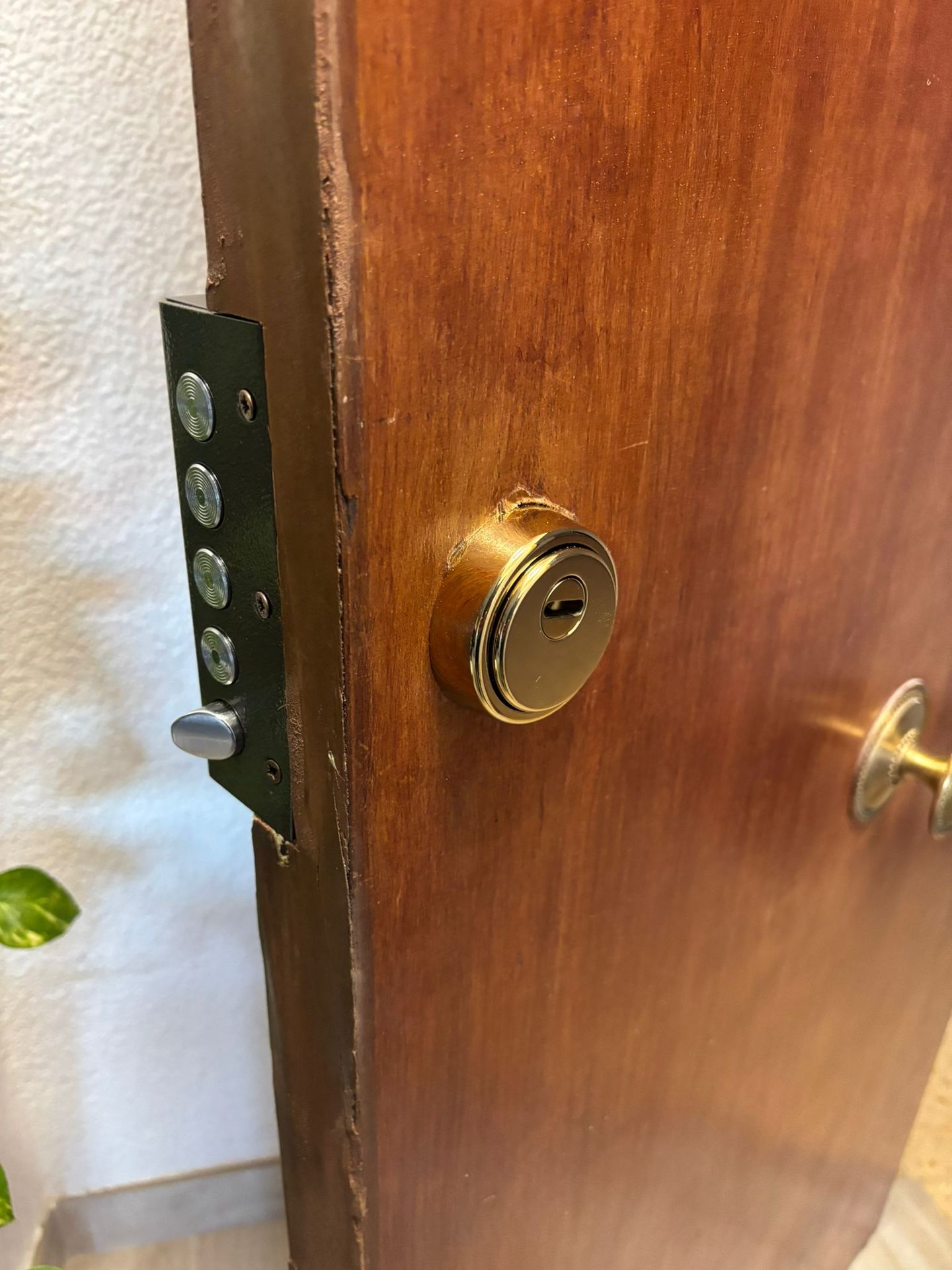 Bombín redondo dorado instalado en puerta de madera con cerradura multipunto vista en el canto