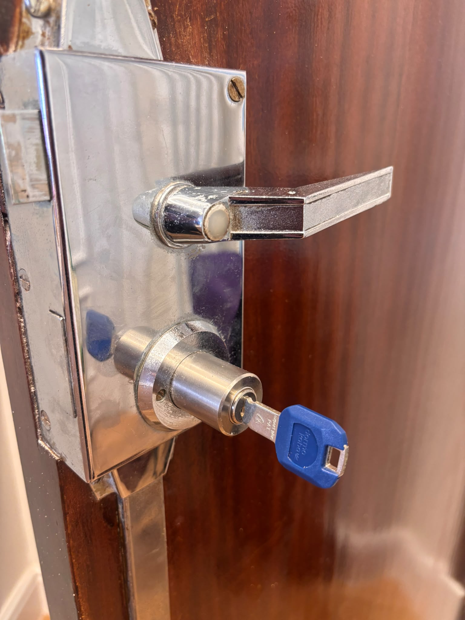 Cerradura con llave azul y maneta en puerta madera