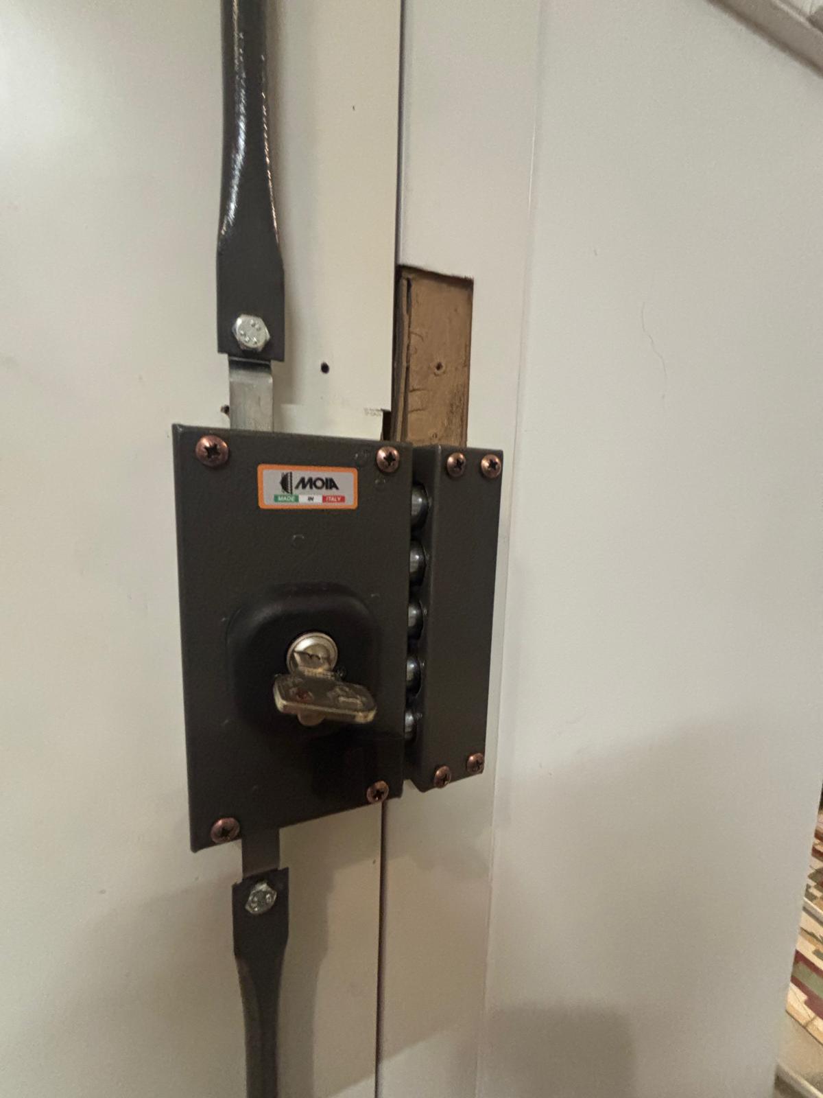 Cerrojo de seguridad MOIA Made in Italy con puntos de anclaje y barra vertical instalado en puerta blanca